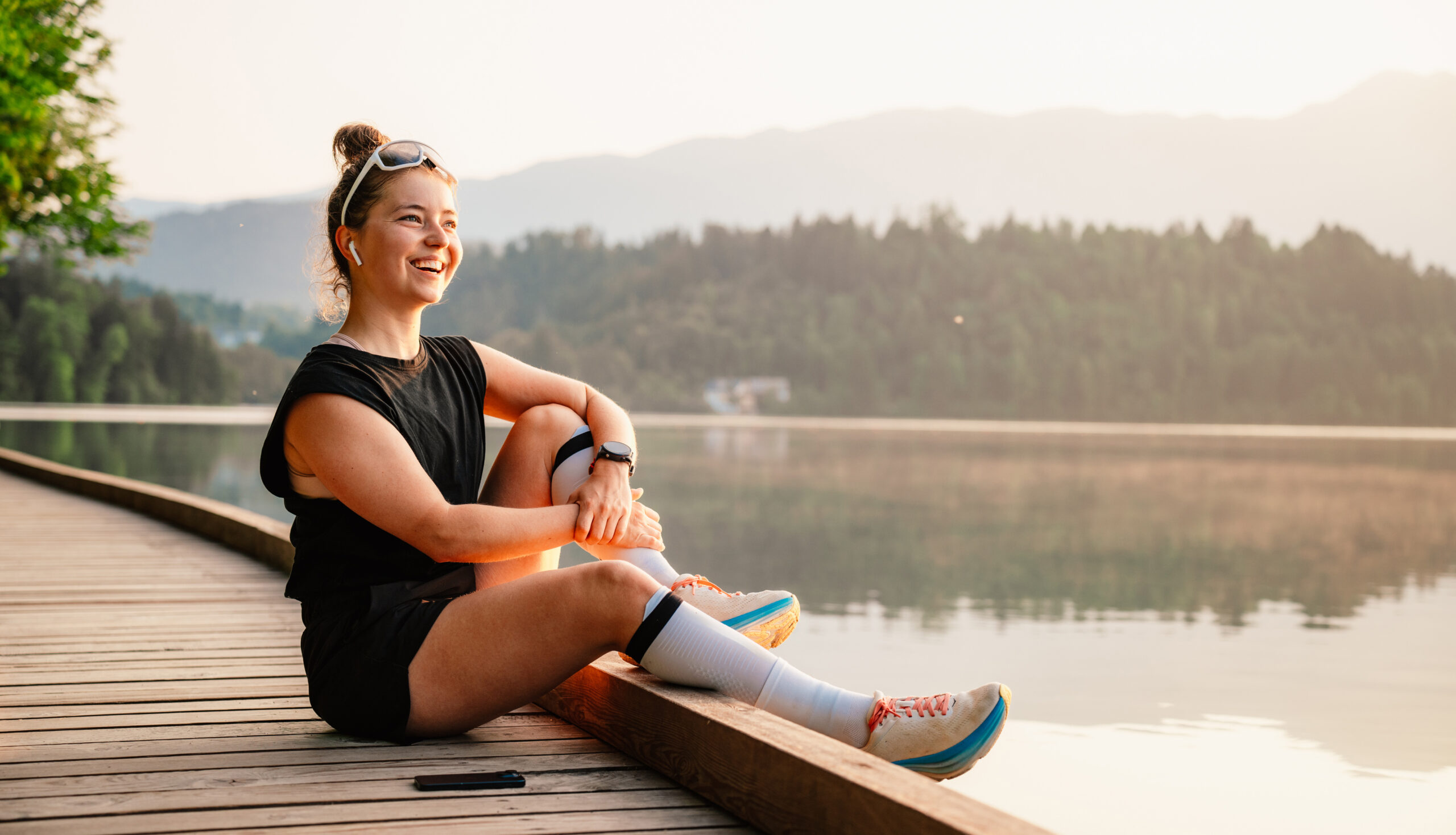 Woman running by the lake on a sunny day. Active lifestyle and outdoor fitness concept.